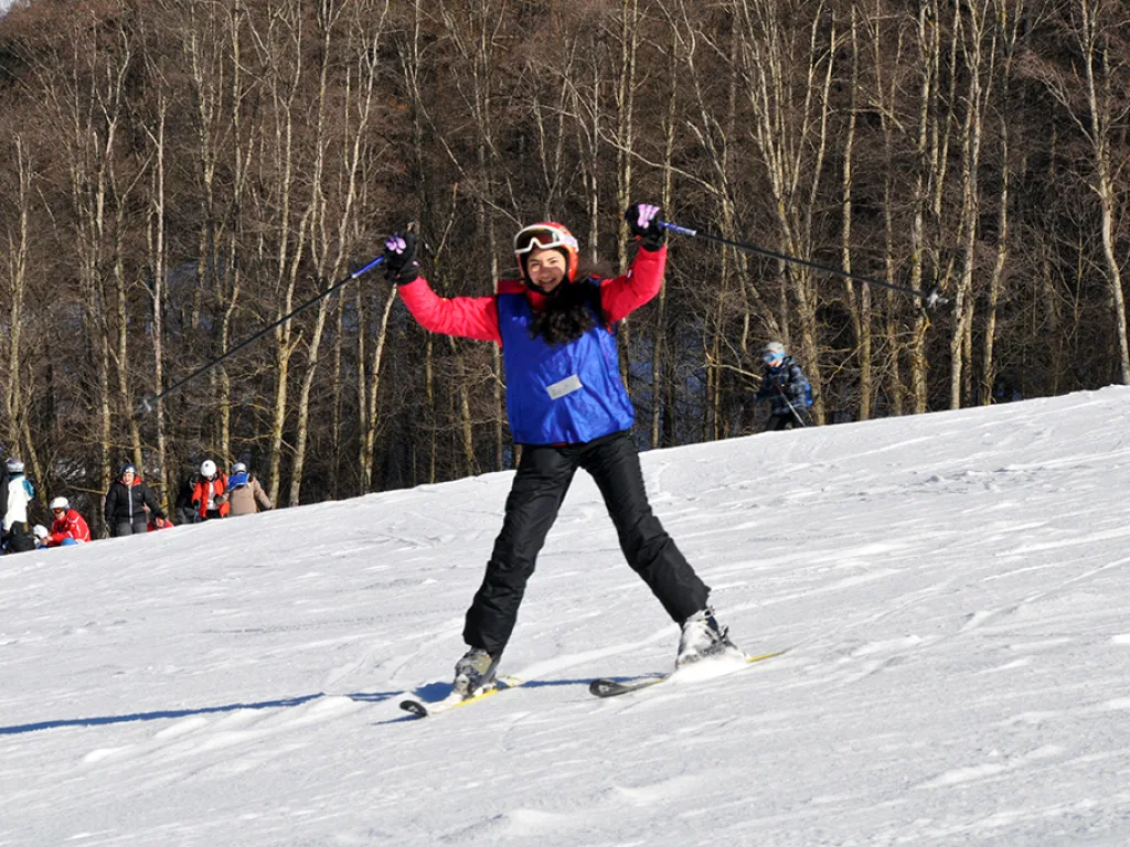 Skifahrerin breitet auf der Piste die Arme aus.
